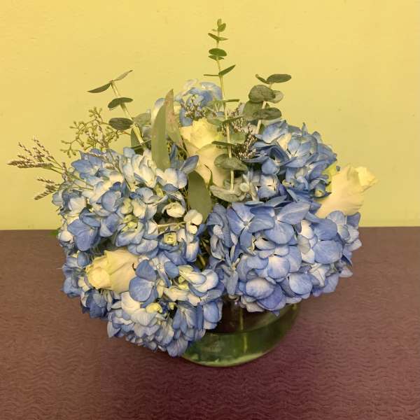 Blue hydrangea bouquet with white roses in a glass vase