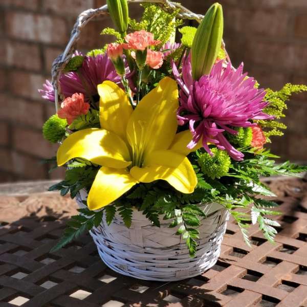 Basket arrangement with yellow lily and pink flowers