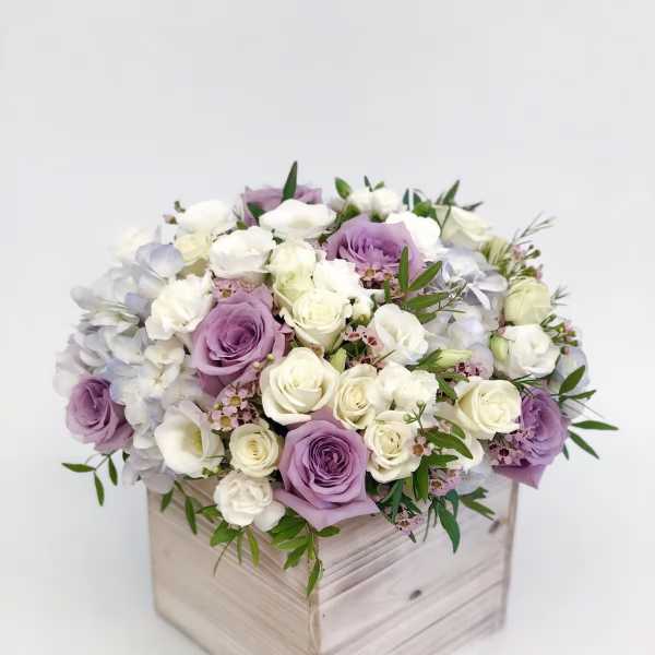 Lavender and white roses arranged in a wooden box