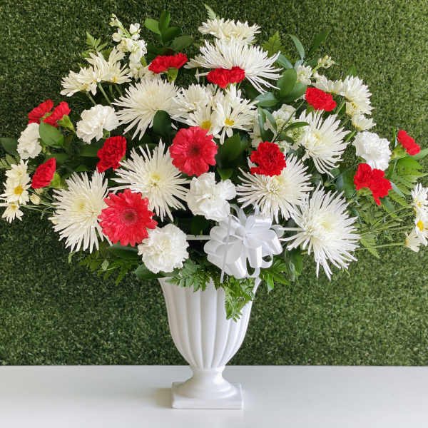 White and red floral arrangement in a white urn vase