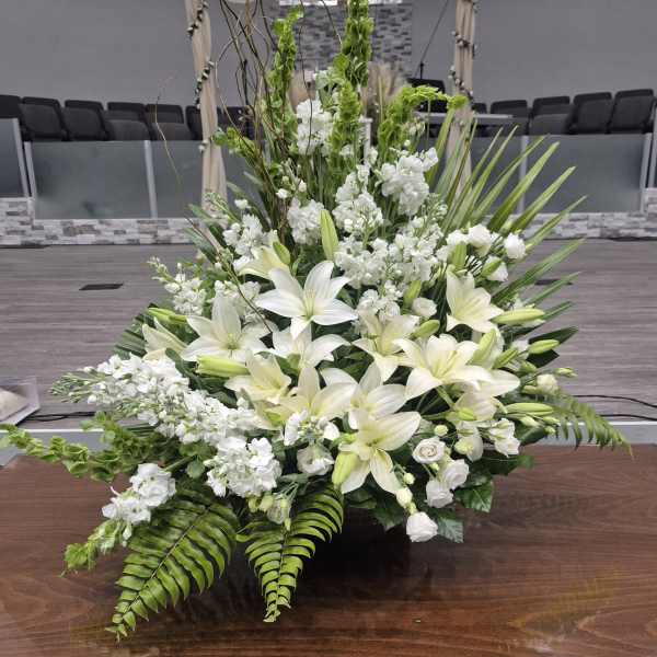 Large white floral arrangement with lilies and greenery in a church setting