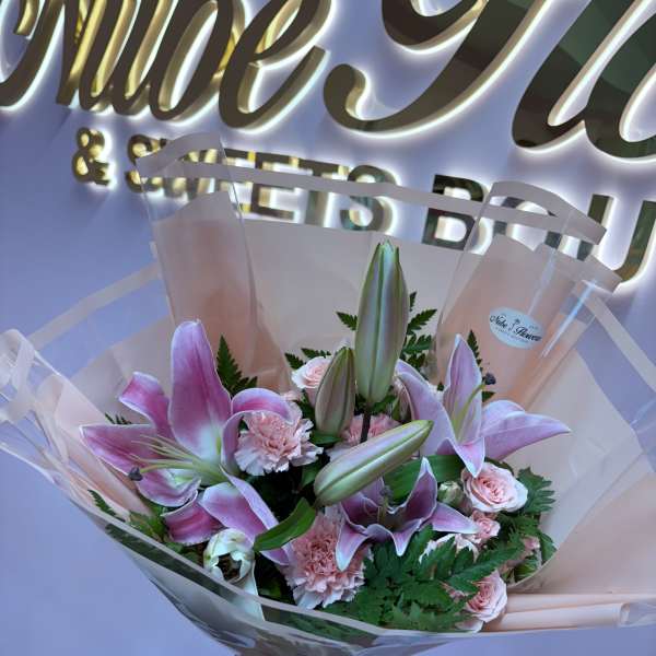 Pink lilies and carnations in a wrapped bouquet