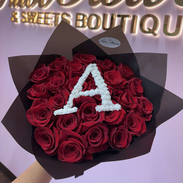 Bouquet of red roses wrapped in black paper with a white letter A