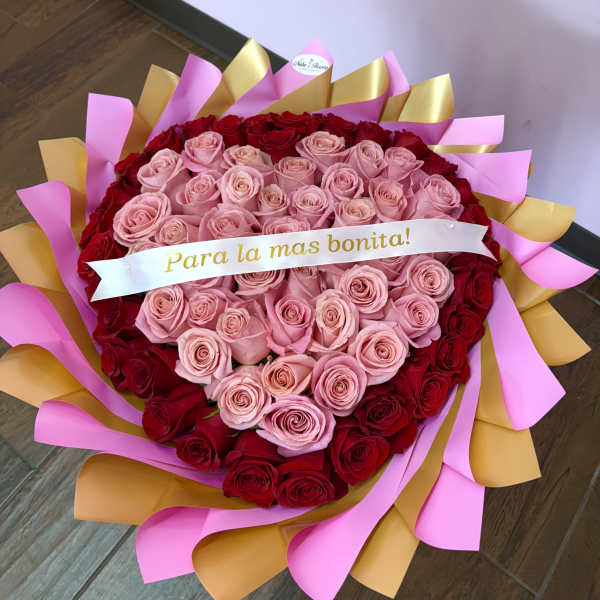 Heart-shaped bouquet of pink and red roses with a ribbon banner