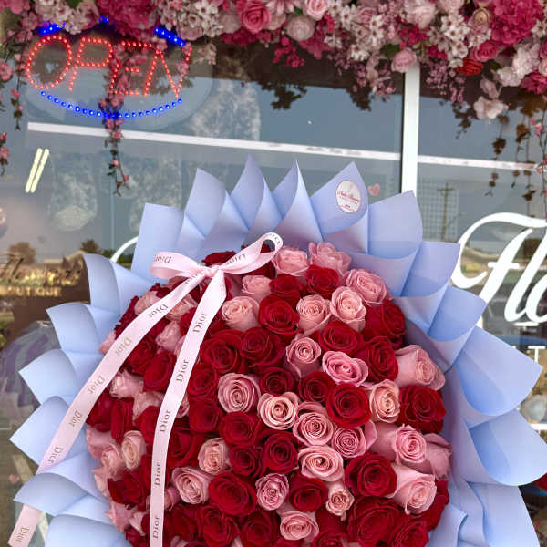 Large bouquet of red and pink roses wrapped in pale blue paper