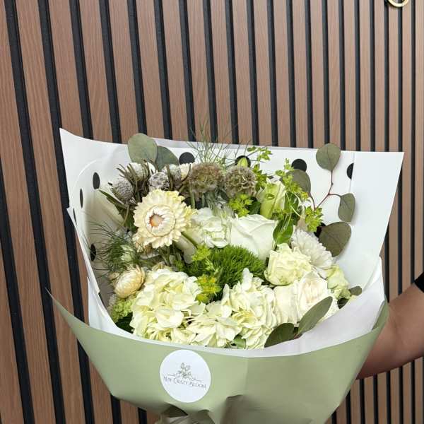 Bouquet of white and pale green flowers wrapped in green paper