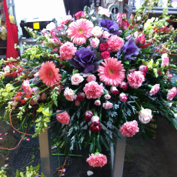 Large mixed floral spray with pink and purple blooms on a stand