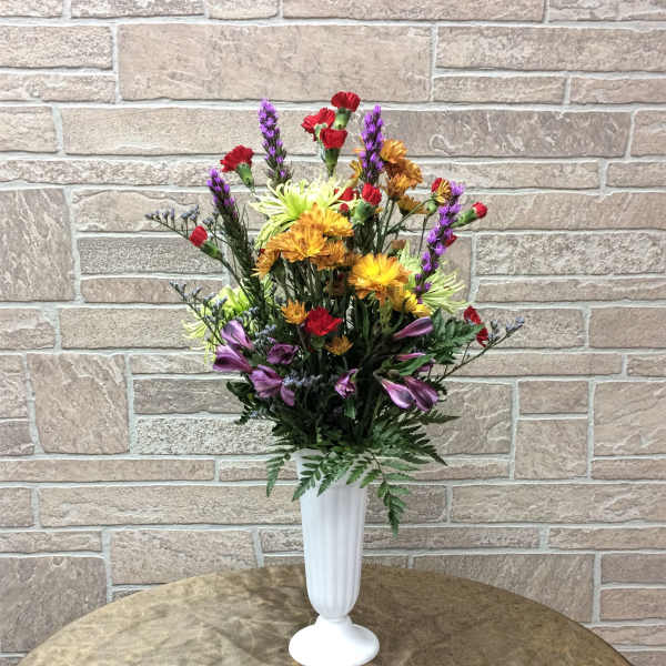 Mixed bouquet in a white pedestal vase with red, purple, and yellow flowers