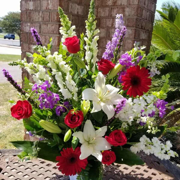 Mixed bouquet with red roses, white lilies, and purple flowers in a vase