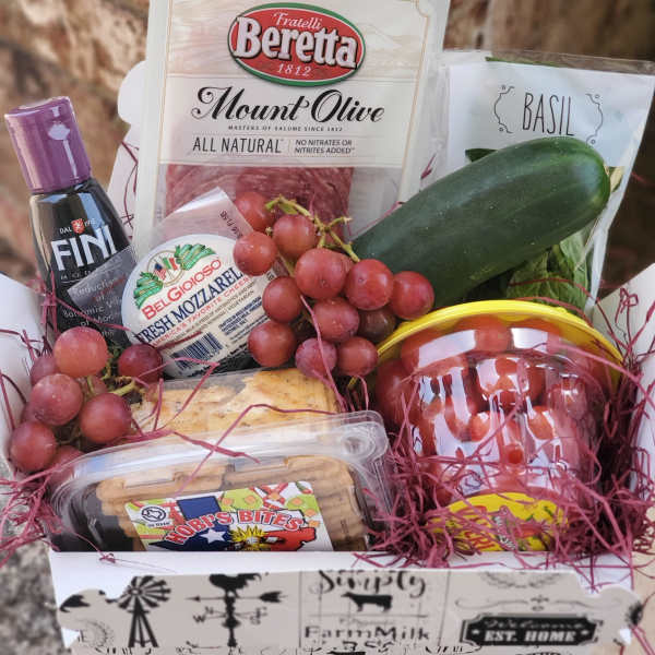Gift basket with salami, cheese, grapes, basil, cucumber, and crackers