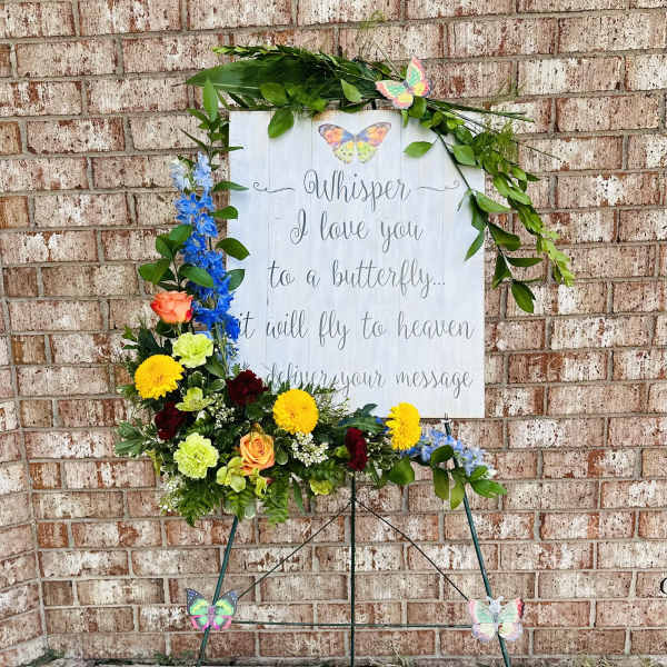 Standing floral tribute with butterflies and a memorial sign