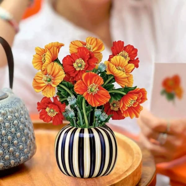 Orange and red flowers in a striped ceramic vase on a table