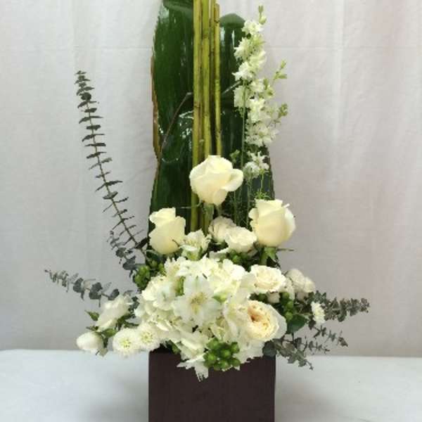 Tall white floral arrangement in a dark square vase