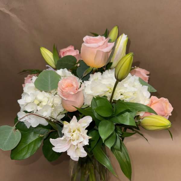 Pink roses and white hydrangeas in a glass vase with lily buds