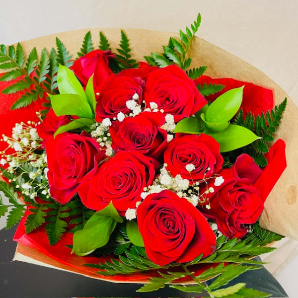 Bouquet of red roses with baby's breath and greenery wrapped in paper
