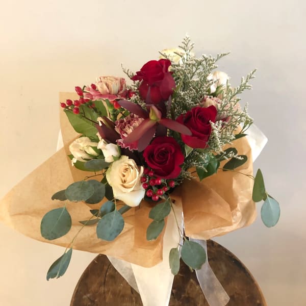 Bouquet of red and cream roses with pink accents wrapped in brown paper