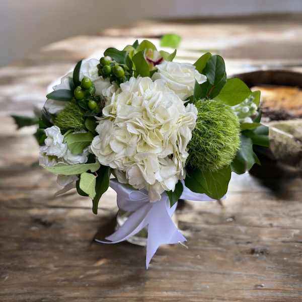 White floral bouquet with green accents and a white ribbon