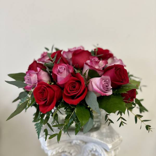 Bouquet of red and pink roses with greenery in a clear vase