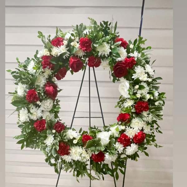 Large red and white floral wreath on a black stand