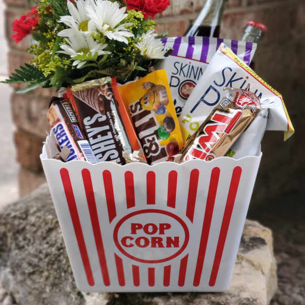 Popcorn bucket gift with candy bars and a small flower bouquet