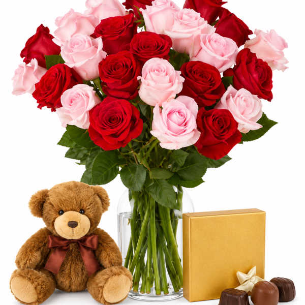 Bouquet of red and pink roses in a glass vase with a teddy bear and chocolates