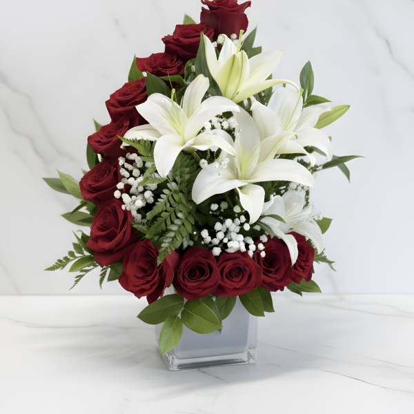 Red roses and white lilies arranged in a clear square vase