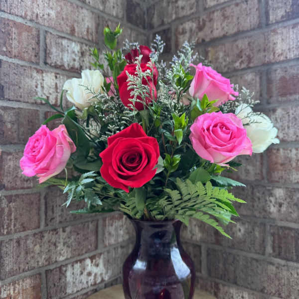 Pink, red, and white roses arranged in a dark glass vase