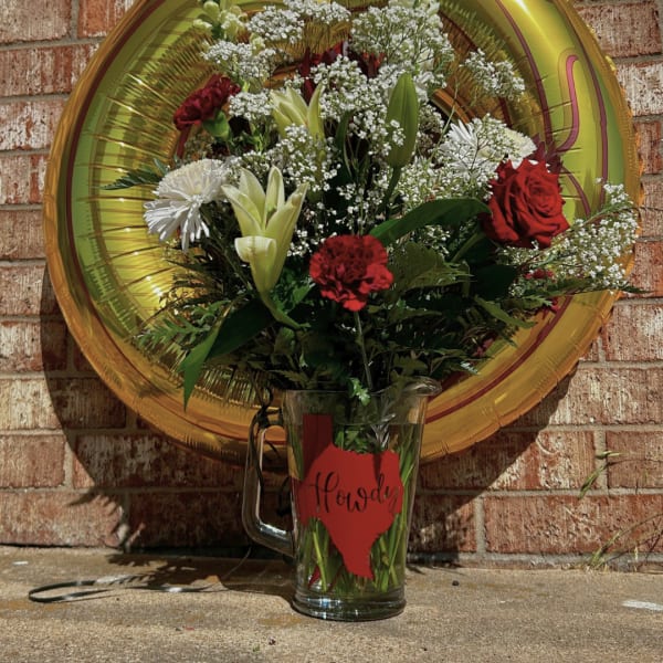 Bouquet of red and white flowers in a glass mug with a gold balloon behind it