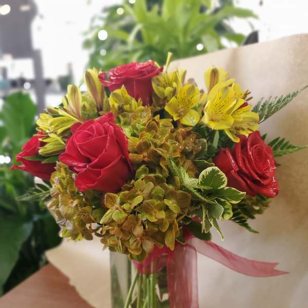 Bouquet of red roses and yellow alstroemeria in a glass vase