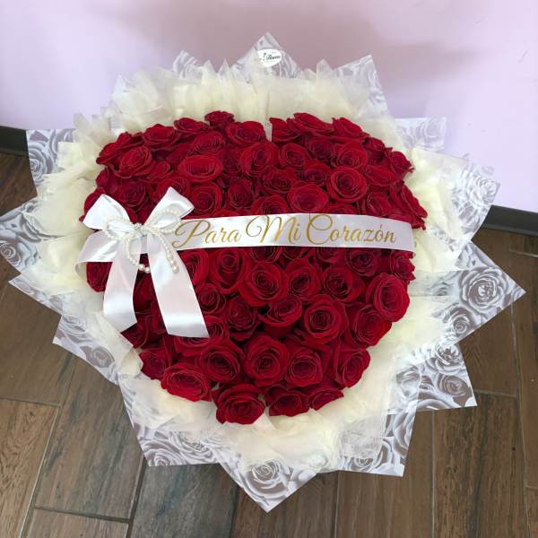 Large bouquet of red roses wrapped in white paper with a ribbon