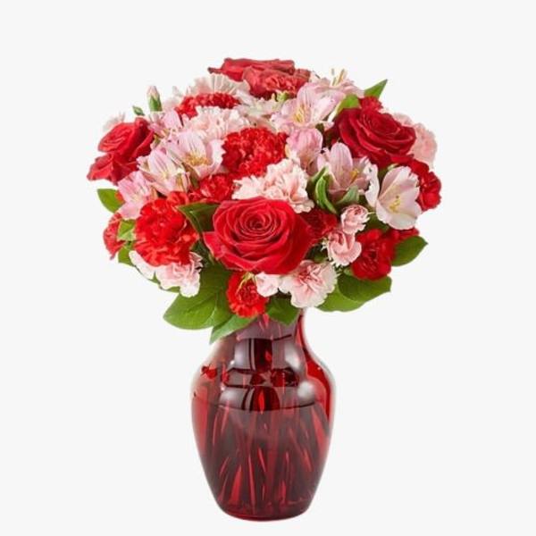 Bouquet of red roses and pink carnations in a red glass vase