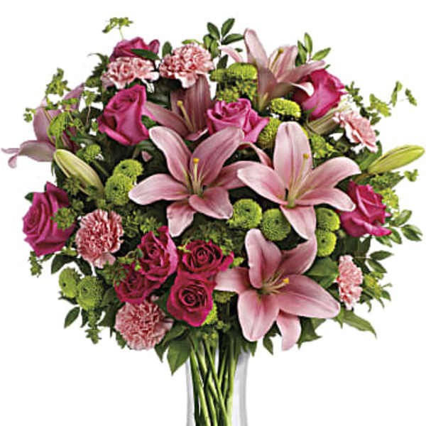 Pink lilies, roses, and carnations in a clear glass vase