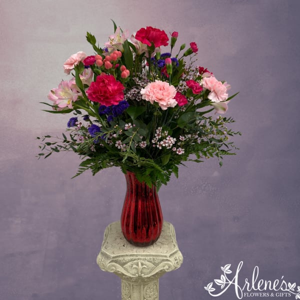 Mixed pink and purple bouquet in a red glass vase