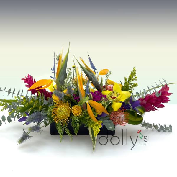 Colorful tropical flower arrangement in a low rectangular container