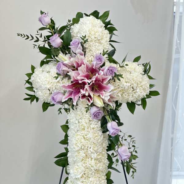 White floral cross with pink lilies and lavender roses on an easel