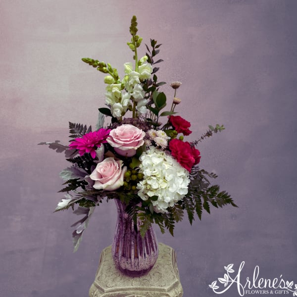 Mixed bouquet in a purple glass vase with pink, white, and magenta flowers