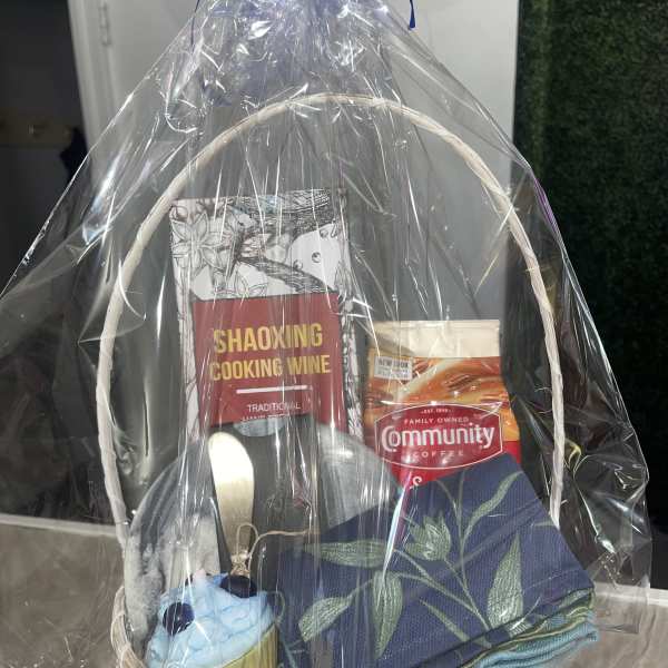Gift basket with cooking wine, coffee, folded napkins, and a cupcake