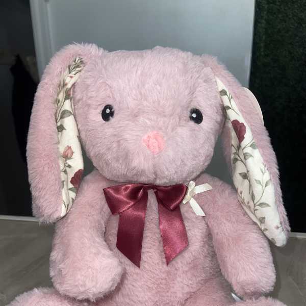 Pink plush bunny with floral-patterned ears and feet, wearing a burgundy bow