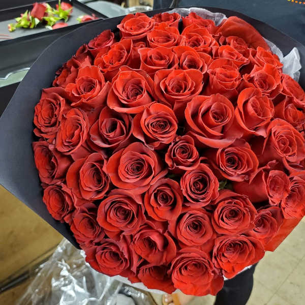 Large bouquet of red roses wrapped in black paper