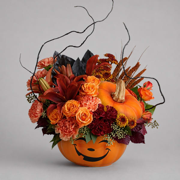 Halloween pumpkin container filled with orange and red flowers