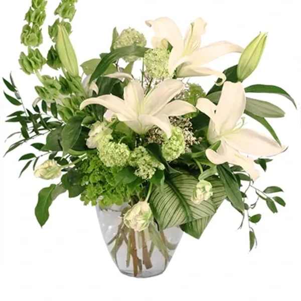 White lilies and green flowers in a clear glass vase