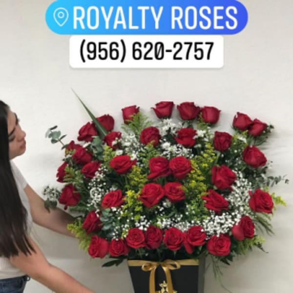 Large red rose arrangement in a black vase with a gold ribbon