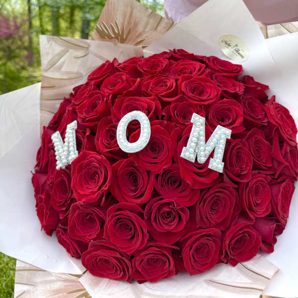 Round bouquet of red roses with pearl letters spelling MOM