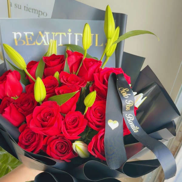 Bouquet of red roses and yellow lily buds wrapped in black paper