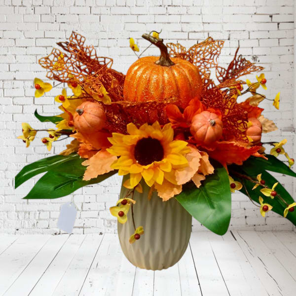 Autumn arrangement with a sunflower, pumpkins, and orange accents in a vase