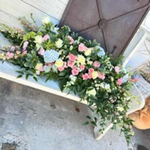 Pastel floral casket spray with pink, white, and blue blooms