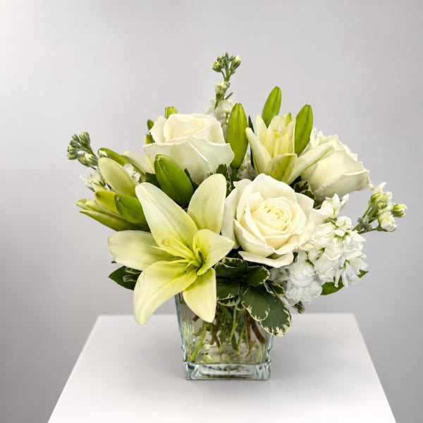 White roses and lilies arranged in a clear glass vase