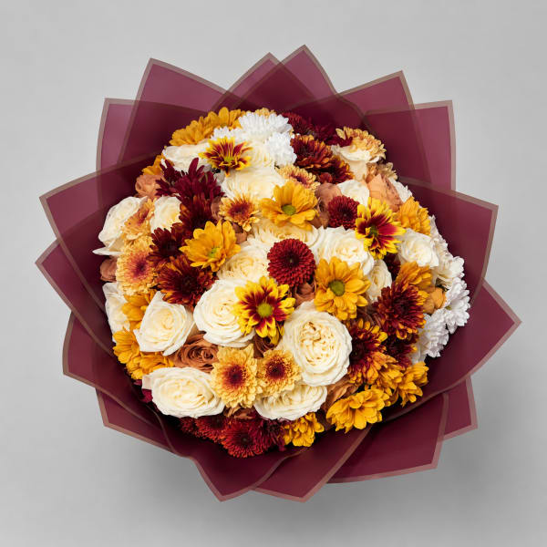 Round bouquet of cream, yellow, and burgundy flowers wrapped in dark plum paper