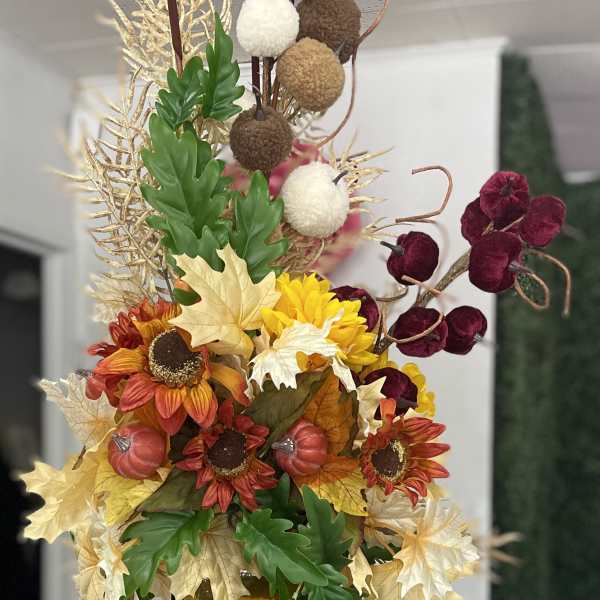 Tall autumn floral arrangement in an amber glass vase