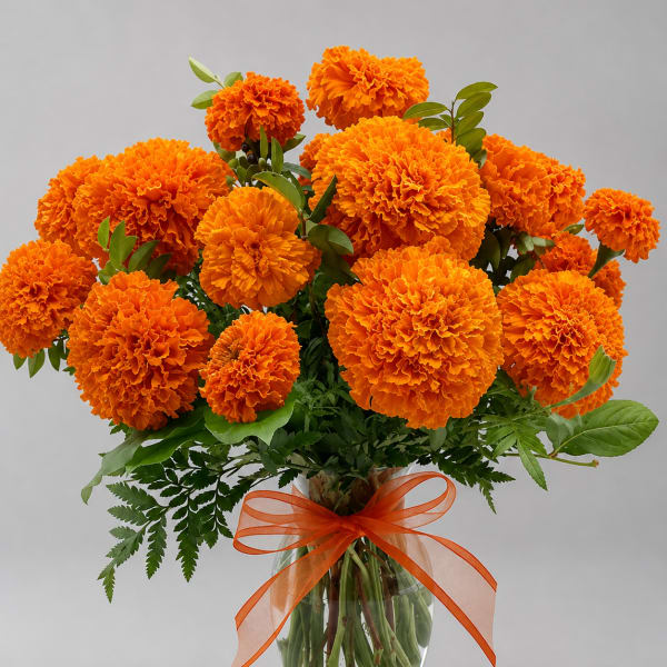 Orange marigold bouquet in a clear glass vase with an orange ribbon